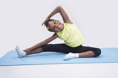 A little girl smiling and  exercising on a gym mat  の写真素材