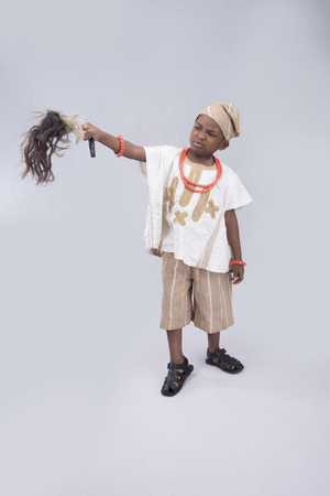 kid in native attire holding a horse tail pointingの写真素材