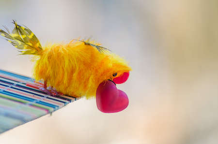bird with red heart in its beak sitting on his house waiting for your soul mate and is ready to give his belovedの写真素材