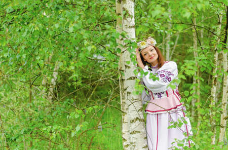 A beautiful girl in a national Belarusian costume against the backdrop of beautiful nature.の写真素材
