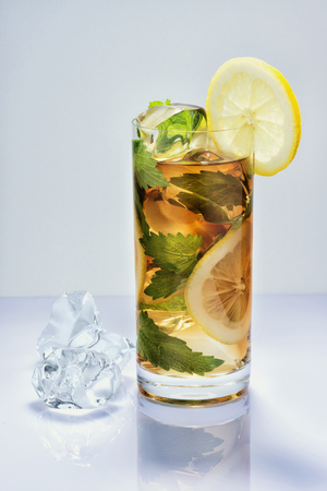 Lemon drink and ice in a glass on a surface with reflectionsの写真素材