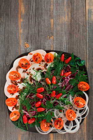 Fresh vegetables, greens and mushrooms on a black ceramic plate in style a rusticの写真素材
