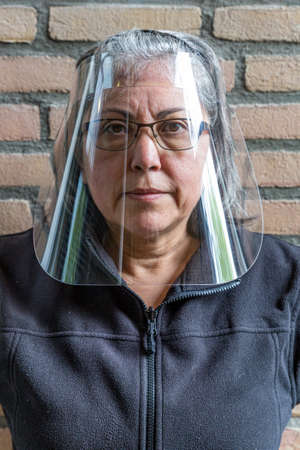 Face shield or protection medical screen on a mature woman wearing glasses to prevent the spread of outbreak, new lifestyle, front viewの写真素材