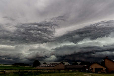 Overcast sky with very dark clouds from heavy storm above field and farm in Beek, South Limburg in...