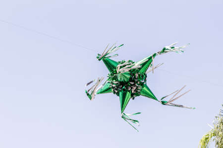 Metallic green paper piÃ±ata suspended in the air with a blue sky background, wonderful mexican...