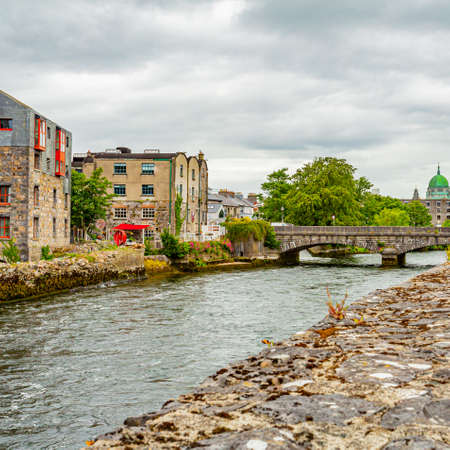 View of the William O'Brien on the Corrib river from the pedestrian walkway, the green dome of the cathedral in the background, Galway waterways, cloudy day in Galway, Connacht province, Irelandのeditorial素材