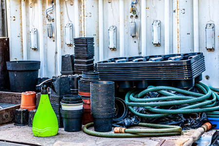 Accumulation of objects on a work table with a rusty metal wall with neon lamps in a greenhouse with...