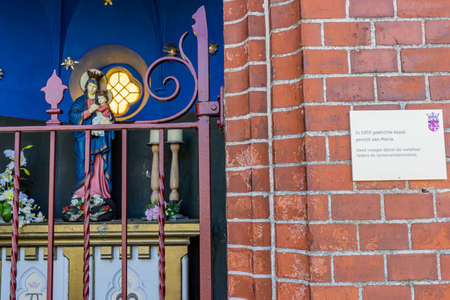Beek, South Limburg, Netherlands. November 18, 2020. Metal sign that says: 1903 Lady Chapel Kelmond was founded, metal fence and the statue of the Virgin Mary with the baby Jesus, flowers and candlesのeditorial素材