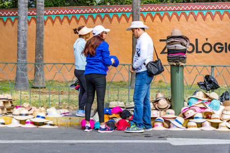 Guadalajara, Jalisco / Mexico. February 4, 2017. Male seller selling hats on the street at the entrance to the zoo to a female tourist, different types of hats with details in different colorsのeditorial素材