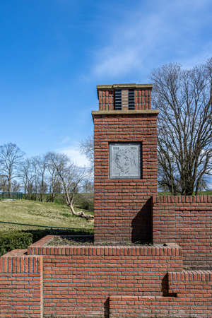Medemblik, North Holland, Netherlands. April 14, 2021. Queen Emma memorial with a blue sky and bare trees in the background. Plate with the profile and inscription 1858 - 1934. Royalty Travel Guideのeditorial素材