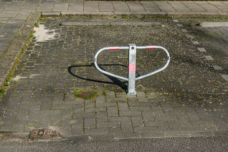 Car parking lock security barrier, can be folded, metal with red lines on a stone floor next to a sidewalk, sunny day in the Netherlands. Theft prevention conceptの写真素材
