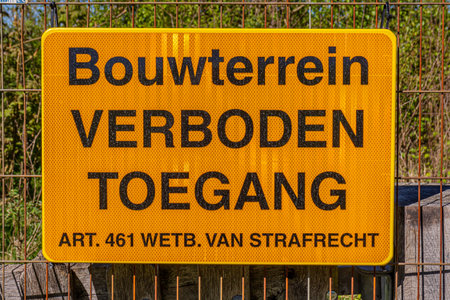 Yellow metal plate that says Construction site No Trespassing. Art 461 law. of criminal law in Dutch which means: Construction Site, No Trespassing. Article 461 law. of criminal lawの写真素材