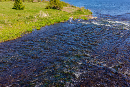 Waters of a stream flowing between stones into the Oude Maas river, seen from the Molenplas nature...