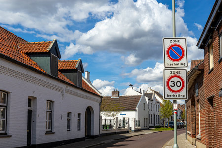 Architectural landscape of street with traffic signs against blue sky with clouds, 30 km zone and No parking, houses with white walls, sunny day in Thorn old Dutch town in Midden-Limburg, Netherlandsの写真素材