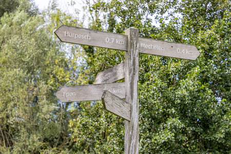 Hiking routes sign at crossroads in Gulpen-Wittem region, towards towns: Hurpesch, Mechelen, Epen and Elzet, green foliage of trees in blurred background, sunny day in South Limburg, Netherlandsの写真素材