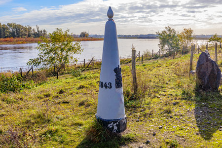 Border marker between Belgium and Holland in Belgian nature reserve De Wissen, Maas river in misty background, sunny autumn day in Dilsen-Stokkem, Belgium. Treaty of Maastricht of 1843の写真素材