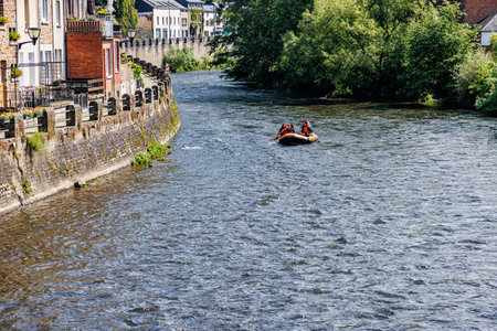 La Roche-en-Ardenne, Belgium. June 4, 2024. Inflatable rowboat sailing on Ourthe river, buildings, stone walls on edge and green trees, tourists enjoying a sunny summer dayのeditorial素材