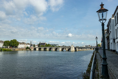 River Meuse with Servatius Bridge or Sint Servaasbrug in background, street lamps on cobblestone...