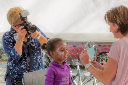 Beek, South Limburg, Netherlands. September 27, 2014. Brunette girl with professionally painted fantasy face, adult woman showing result in mirror and photographer taking photos from behindのeditorial素材