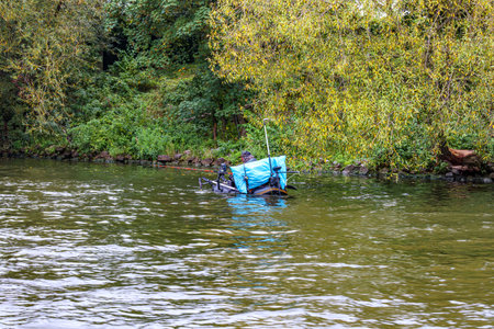River Meuse with calm water, back view of man in inflatable fishing boat, peacefully fishing,...