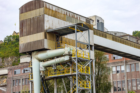 Abandoned and ruined industrial complex with storage tower at bulk cargo terminal on bank of Meuse...