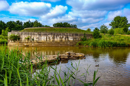 Circular viewpoint on hill with tributary pond of Demen River in Kapermolen Park, lush trees against blue sky in background, cloudy day on the outskirts of Hasselt, Belgiumの写真素材