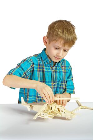 A boy builds a wooden helicopter from partsの写真素材