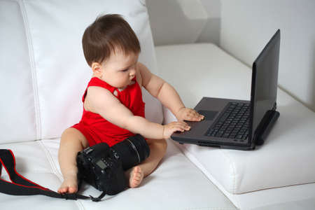 Baby is playing with laptop and camera