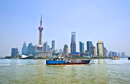 View of the Pudong financial district from the other side of the Huangpu River with a blue boat in the foregroundのeditorial素材