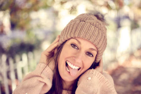 Romantic positive young caucasian woman smiles happy and making a face with her tongue, has white...
