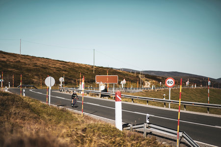 A woman cyclist training on a lonely road on a sunny day wearing a black jersey and bib shorts and a white helmet.の写真素材