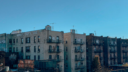 Classic urban buildings in The Bronx with graffiti, fire escapes, and clear blue sky, showcasing the neighborhood's gritty charm.の写真素材