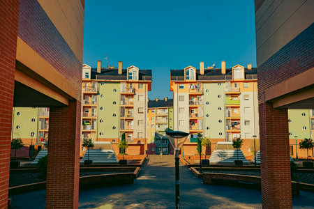 A modern residential complex with green facades and circular windows, framed by brick structures....