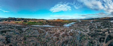 A stunning panoramic aerial view shows a winding river cutting through expansive marshlands with...