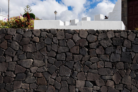Close-up and frontal view of a rustic basalt stone wall with rough texture and organic pattern, ideal as architectural or design background.の写真素材