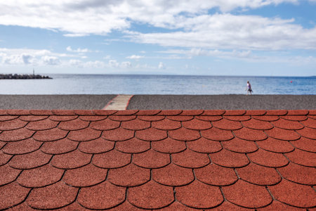 Symmetrical coastal composition with red rooftop texture and empty beach walkway, capturing a tranquil moment at the start of summer.の写真素材