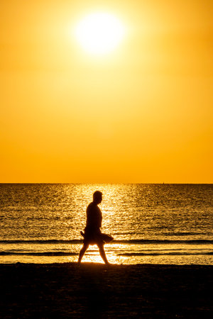 Active older adults enjoy a quiet morning on the Mediterranean coast, walking or bathing during a peaceful golden sunrise in Cyprus.の写真素材
