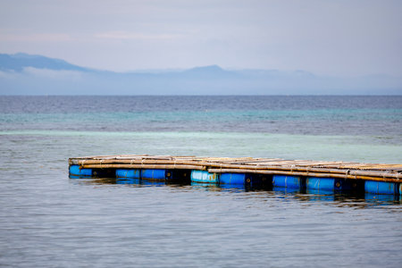 Handmade dock or fish cage platform floating near the shore, commonly used in island aquaculture and coastal tourismの写真素材