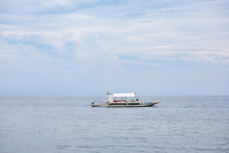Solitary boat with canopy on calm waters, showing traditional maritime life amid a moody tropical atmosphereの写真素材