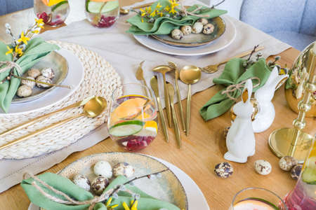 Plates, golden cutlery, glasses, gift box, festive branch decoration, candles