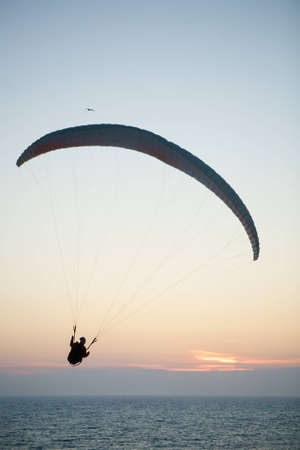 Paraglider parachute flying over the sea at sunset.の写真素材