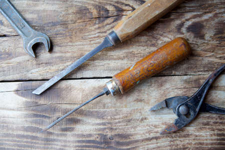 A set of working vintage metalwork and repair tools lying on a wooden surface.の写真素材