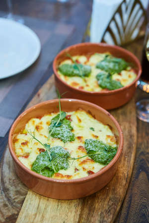 Vegetable casserole with cheese in a rural kitchen. Food in clay dishes from the oven.の写真素材