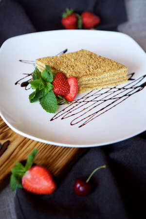 Close-up dessert is a piece of cake or puff cake with cream. The food is decorated with fresh fruit, strawberries and green mint leaves. Concept of confectioneryの写真素材