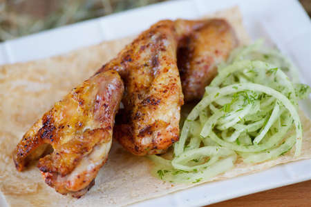 Pieces of fried poultry meat on pita bread, served with fresh vegetables on a plate and a wooden board. Cooking meat and recipes.の写真素材