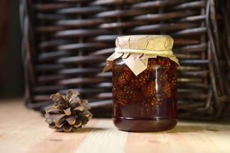 Jam from pine cones of brown color lies about a wicker basket.の写真素材