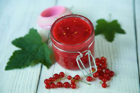 A glass jar filled with boiled jam from red currant. Sweets and desserts.の写真素材