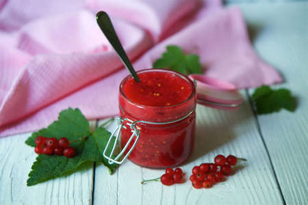 A glass jar filled with boiled jam from red currant. Sweets and desserts.の写真素材