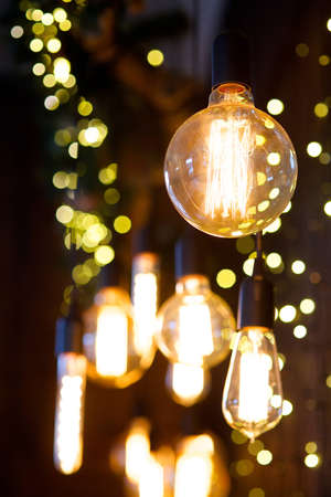 Vintage lamps with wires hang on the wall in the old-fashioned interior. In the background glare.の写真素材