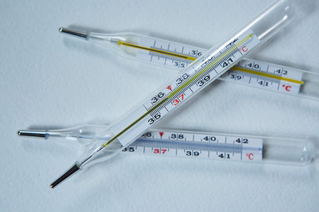 Three classic mercury thermometers with a scale of degrees Celsius lie on a clean white background. Concept of recovery from infection, virusの写真素材